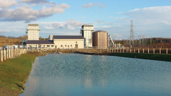 The York Energy Centre (YEC) showing the control room (low building), fire water tank, two stacks (70 ft.) and the plant storm water management pond. The gas turbine and generator enclosures are behind the control room.