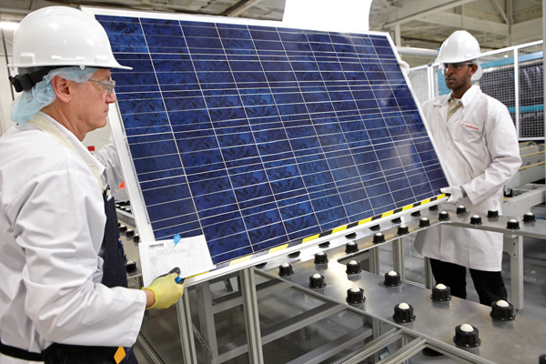 Technicians handle a solar module at Canadian Solar’s new manufacturing plant in Guelph, Ontario. Canadian Solar Inc. is one of the world’s largest solar companies, and a vertically integrated manufacturer, from ingots to wafers to solar cells to modules. The plant, first announced August 11 2010, will be capable of manufacturing 200 megawatts of solar modules a year while employing approximately 500 people in the process. 	Courtesy Canadian Solar