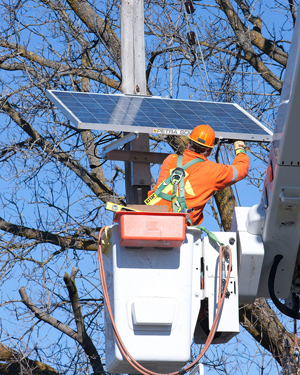 Halton Hills Hydro power line technician Hessel Faber connects one of the utility's new solar-smart grid panels at a launch event for the innovative project. (CNW Group/Halton Hills Hydro)