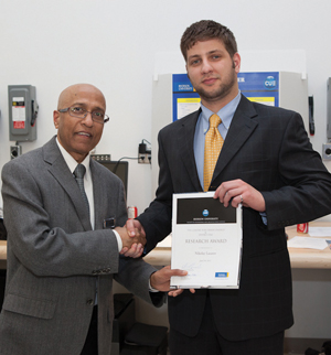 Bob Singh, research director in several of the above programs, hands researcher Nikolay Lazarov an award for his research.