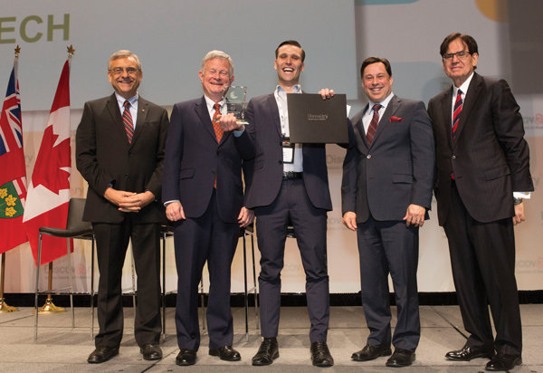 Kyle Bassett receives the McFadden award. L to R: Dr. Tom Corr, President and CEO, Ontario Centres of Excellence; David McFadden; Kyle Bassett; Hon. Brad Duguid, Ontario’s Minister of Economic Development, Employment and Infrastructure; Michael Nobrega, Chair, Ontario Centres of Excellence.  Courtesy Ontario Centres of Excellence